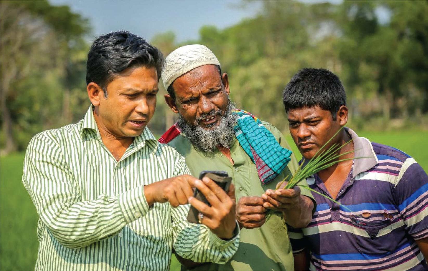 Man Demonstrating Agricultural Mobile App to Farmer and Son in Field